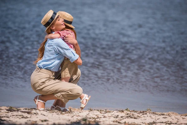 Madre e hija abrazándose en la orilla del mar - foto de stock
