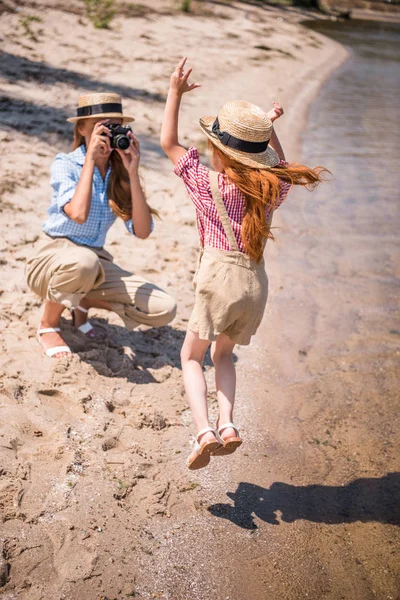 Madre fotografiando hija en la playa - foto de stock