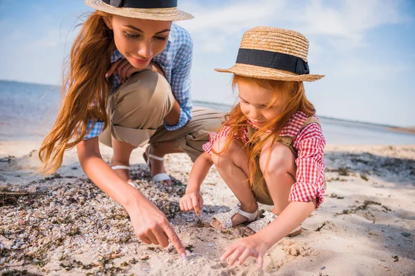 Mother and daughter collecting seashells — Stock Photo