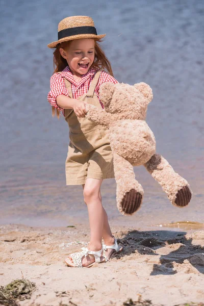Enfant avec ours en peluche au bord de la mer — Photo de stock