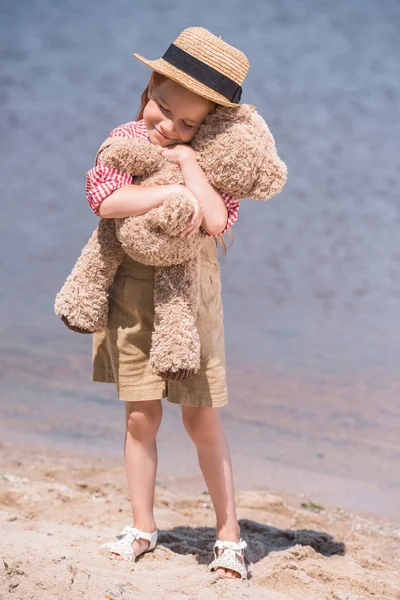 Ребенок с плюшевым мишкой на берегу моря — стоковое фото