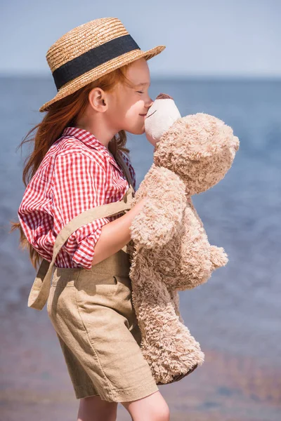 Enfant avec ours en peluche au bord de la mer — Photo de stock
