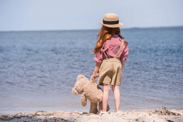 Bambino con orsacchiotto in riva al mare — Foto stock