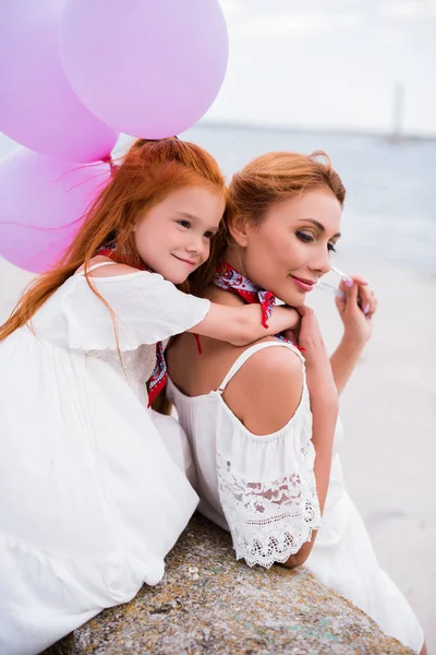 Mère et fille avec des ballons au bord de la mer — Photo de stock