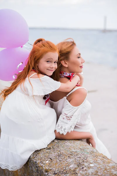 Madre e hija con globos en la orilla del mar - foto de stock