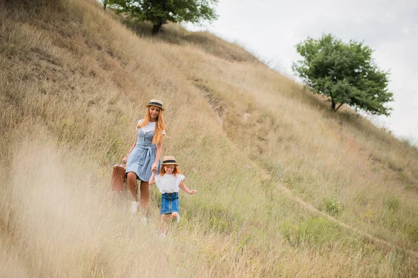 Madre e hija caminando en la colina - foto de stock