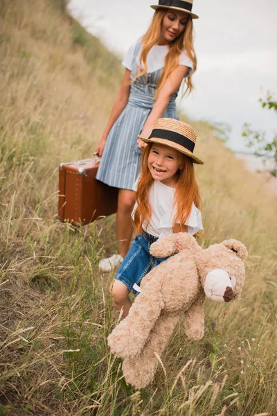 Madre e hija con maleta y osito de peluche - foto de stock