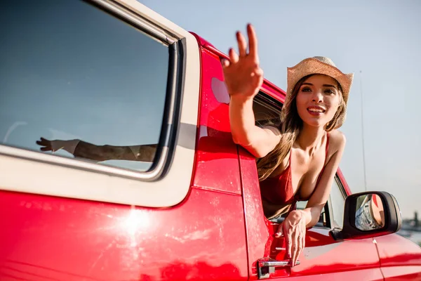 Woman waving out of car window — Stock Photo