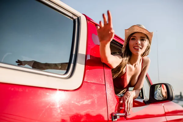 Mujer saludando por la ventana del coche - foto de stock