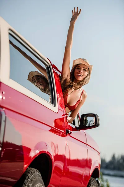 Woman waving out of car window — Stock Photo