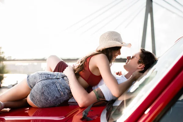 Jeune couple couché sur la voiture — Photo de stock