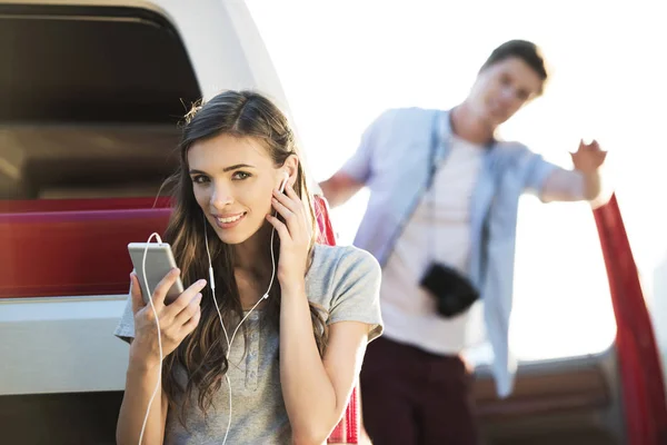 Girl in earphones using smartphone — Stock Photo