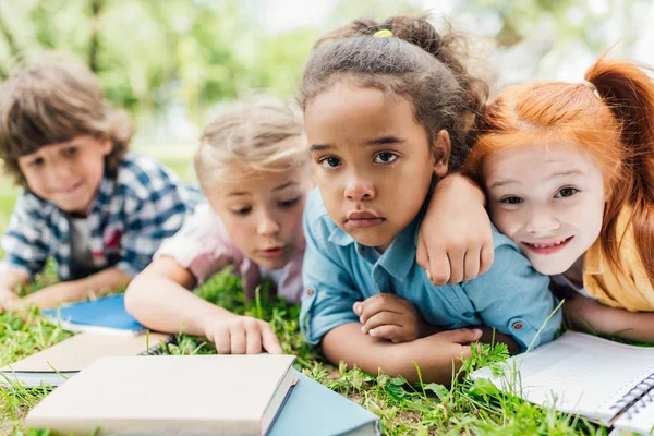 Bambini con libri sdraiati sull'erba — Foto stock