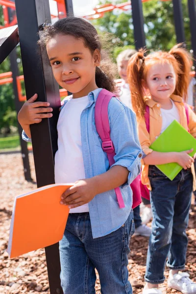 Crianças multiétnicas com livros em playground — Fotografia de Stock