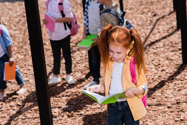 Enfant avec livre sur aire de jeux — Photo de stock