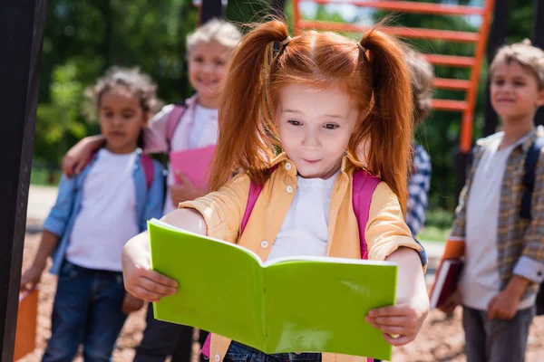 Niño con libro en el parque infantil - foto de stock