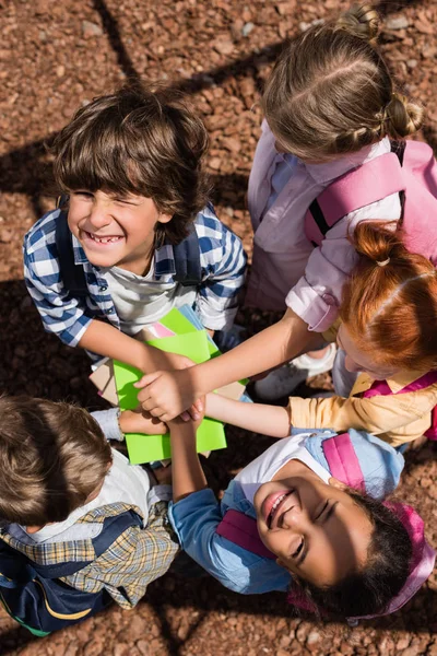 Kids stacking hands above books — Stock Photo