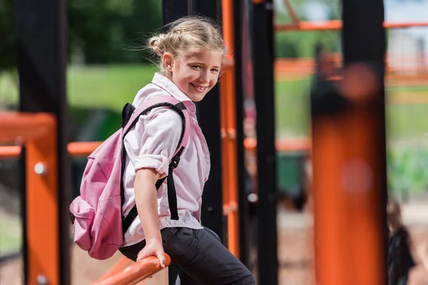 Школярка з рюкзаком на дитячому майданчику — стокове фото