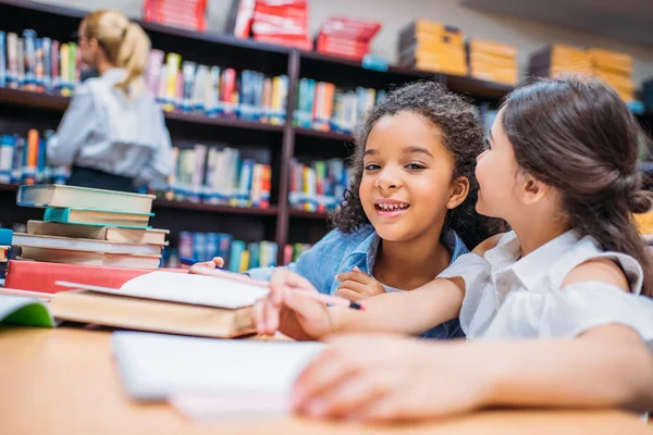 Schulmädchen tratschen in Bibliothek — Stockfoto