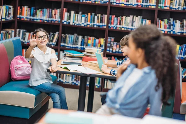 Beautiful schoolgirls greeting at library — Stock Photo