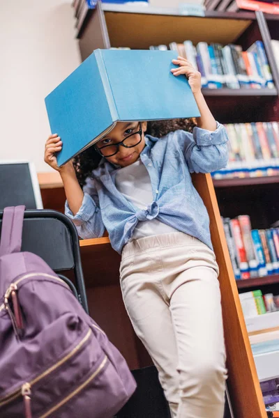 Écolière couvrant la tête avec livre — Photo de stock