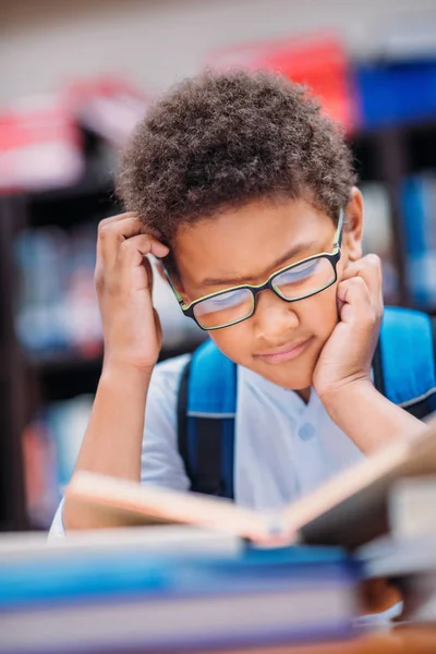 Schoolboy livro de leitura na biblioteca — Fotografia de Stock