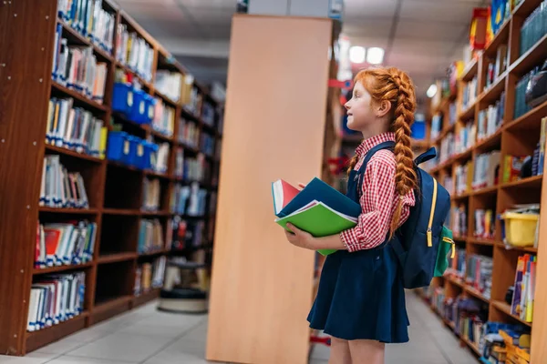 Redhead schoolgirl in library — Stock Photo