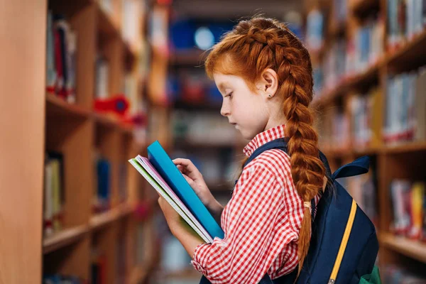 Redhead schoolgirl in library — Stock Photo