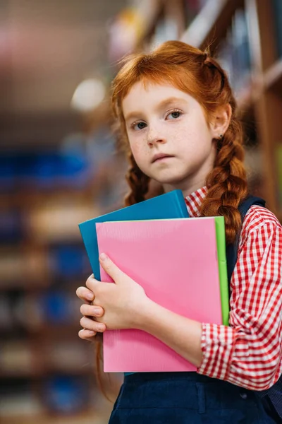 Redhead schoolgirl in library — Stock Photo