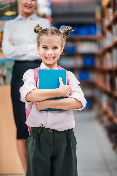 Молодая девушка в библиотеке с учителем — стоковое фото