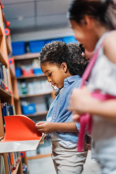 Colegialas que buscan libros en la biblioteca - foto de stock