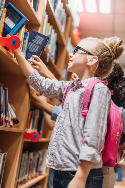 Colegialas elegir libros en la biblioteca - foto de stock