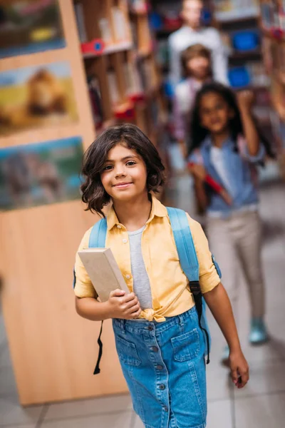 Fille avec livre dans la bibliothèque — Photo de stock