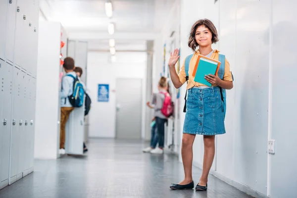 Écolière avec livres dans couloir — Photo de stock