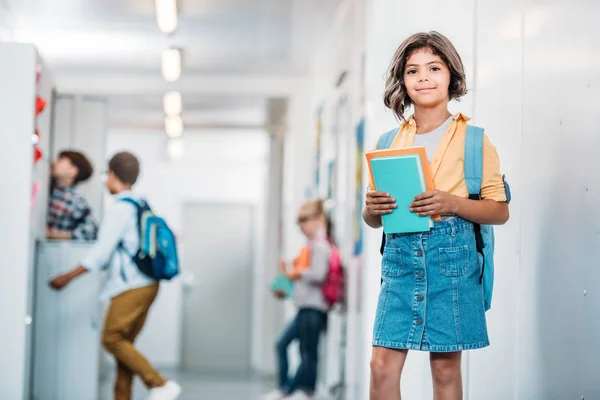 Scolaretta con libri in corridoio — Foto stock