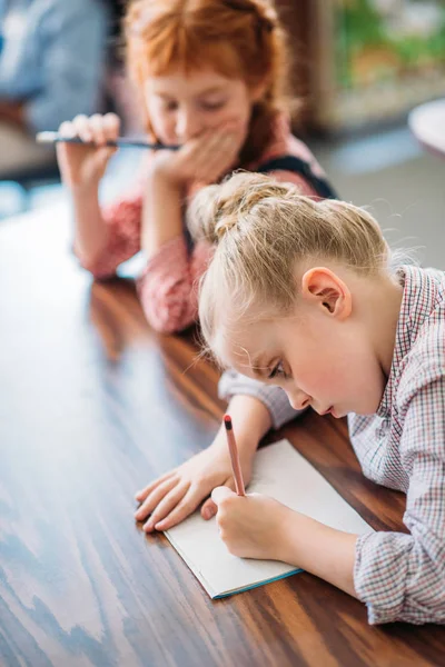 Schoolgirl writing in notebook — Stock Photo