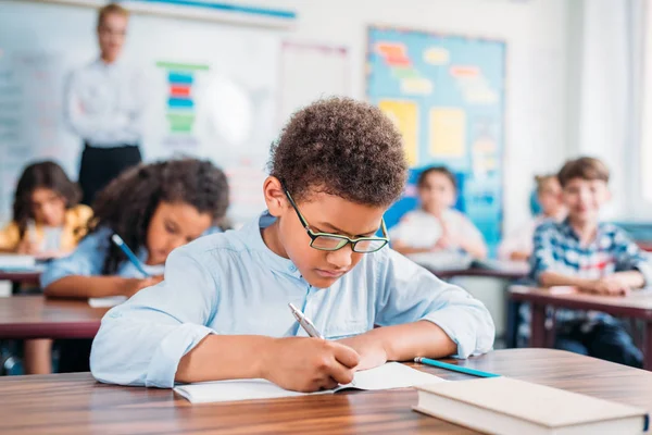 Schoolboy writing in notebook — Stock Photo