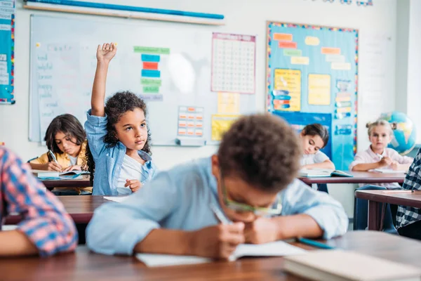 Fille levant la main en classe — Photo de stock