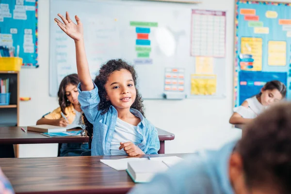 Fille levant la main en classe — Photo de stock