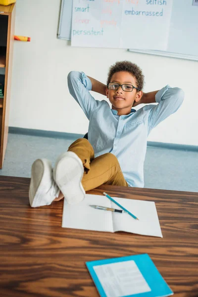 Écolier assis avec les pieds sur la table — Photo de stock