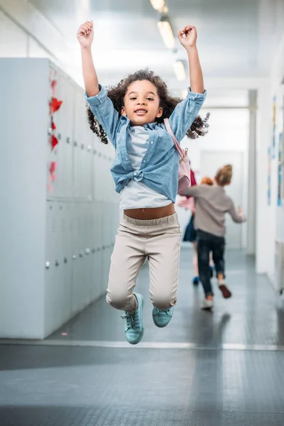 Chica saltando en la escuela pasillo - foto de stock