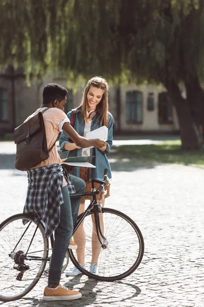 Couple multiethnique avec livres et vélo — Photo de stock