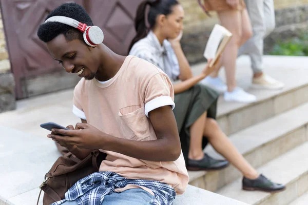 Estudiante usando smartphone y auriculares - foto de stock