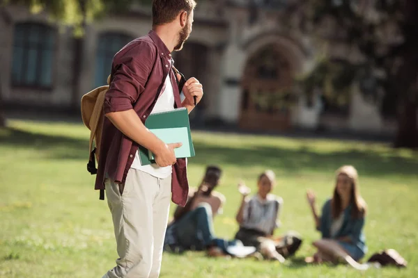 Student mit Büchern schaut Freunde an — Stockfoto