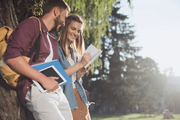 Jóvenes estudiantes leyendo en el parque - foto de stock