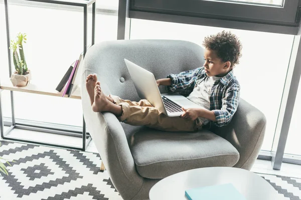 Garçon avec ordinateur portable dans le fauteuil — Photo de stock