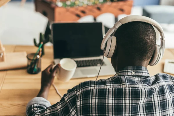 Homem em fones de ouvido usando laptop — Fotografia de Stock