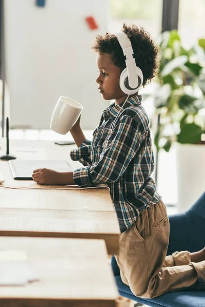 Niño con auriculares y taza - foto de stock