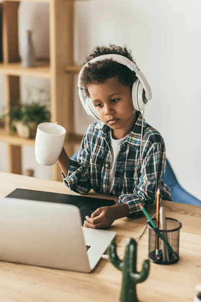 Мальчик в наушниках смотрит на ноутбук — стоковое фото