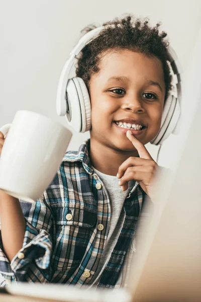 Хлопчик з навушниками дивиться на ноутбук — стокове фото